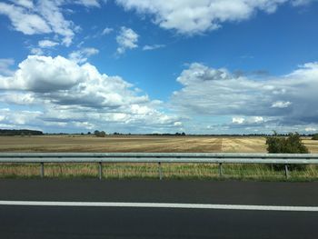 View of field against cloudy sky