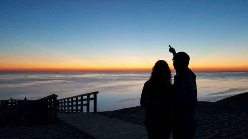 Silhouette of young couple enjoying view of lake michigan at sunset from sleeping bear dunes 