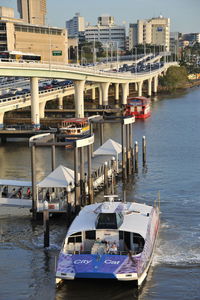 Boats moored at harbor against buildings in city