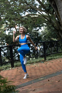 Full length of young woman standing against trees