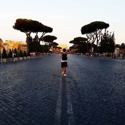 Rear view of woman standing by tree against sky