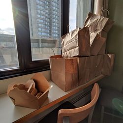 Close-up of table and chairs at windows and a breakfast from catering in craft paper box