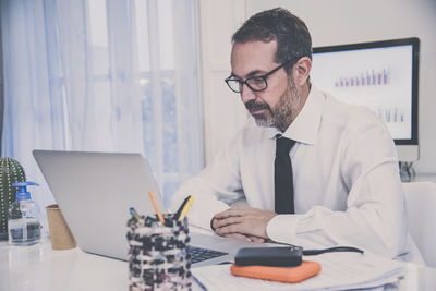 Business man working with laptop sitting at the desk. male works at computer communicate online 