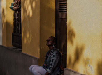 Woman sitting against house