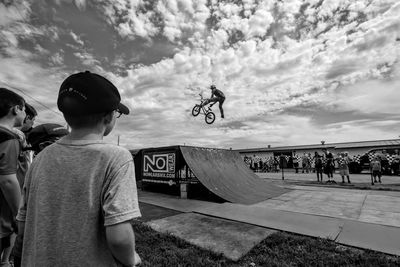 Rear view of man skateboarding on skateboard against sky