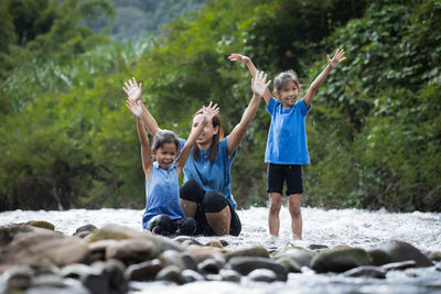 Cheerful mother with with daughter playing in river