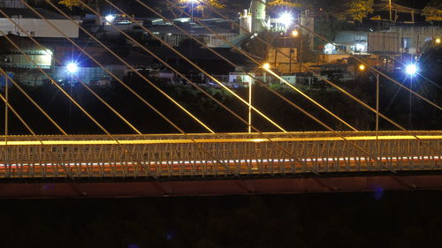 Illuminated bridge in city against sky at night