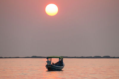 Boat in sea against clear sky during sunset