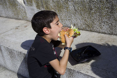 High angle view of eating burger by wall