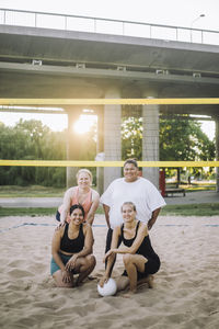 Portrait of smiling women posing near net while playing volleyball