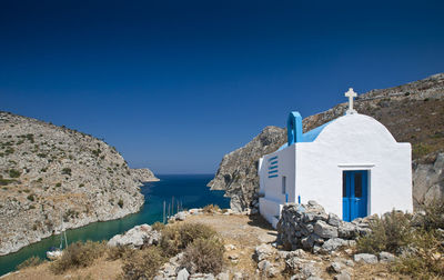 Chapel by sea against clear blue sky