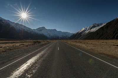 Road by mountains against sky