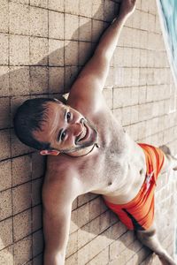 High angle portrait of young man sitting against wall