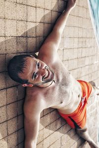 Portrait of young man lying down by swimming pool