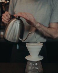 Midsection of man pouring coffee in cup on table