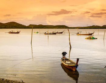 Boat moored in sea against sky during sunset