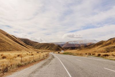 Road leading towards mountains against sky