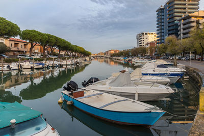 Boats moored at harbor by buildings in city