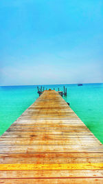 Pier over sea against clear blue sky