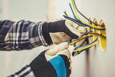 Close-up of man working on cables on wall