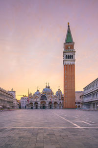 Tower amidst buildings against sky during sunset