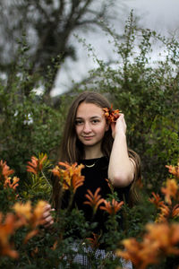 Portrait of smiling young woman standing against trees