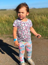 Full length portrait of girl standing against plants and sky