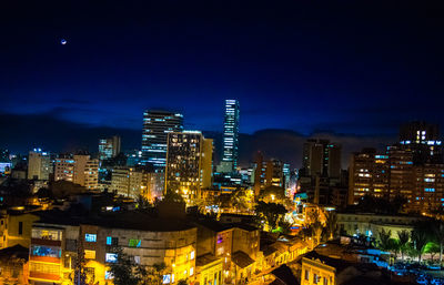 Illuminated buildings in city against sky at night