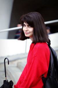 Young woman in red sweater, girl, brown hair, dark eyes, black umbrella, bag on back, short haircut