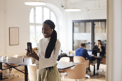 Young woman using mobile phone while sitting at home