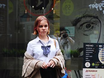 Portrait of woman standing against graffiti wall