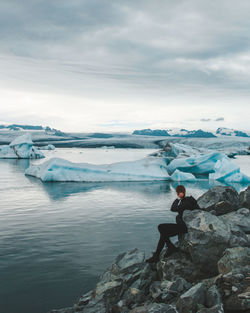 Man standing on rocks against sky during winter