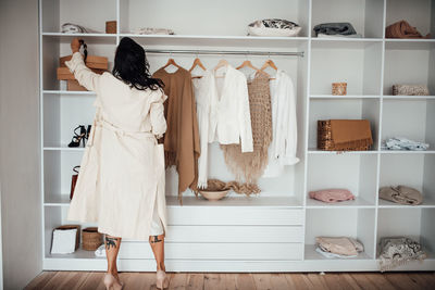 Woman in white dress standing by closet at home
