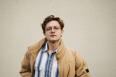 Portrait of young man against beige wall