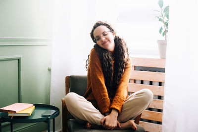 Young woman sitting on sofa at home