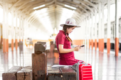 Portrait of young woman using mobile phone while standing in factory