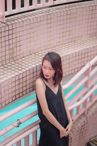 Portrait of smiling young woman standing against brick wall