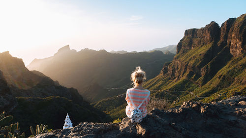 Rear view of man standing on mountain against sky