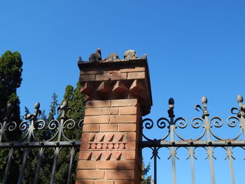 Low angle view of gate against clear blue sky