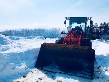 Snow on field by road against sky during winter