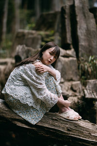 Portrait of young woman sitting on wood