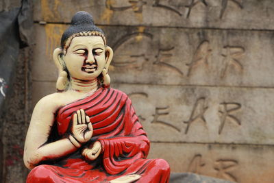 Statue of buddha against wall of building