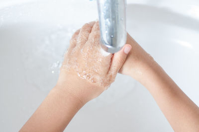 Close-up of person washing hands under faucet