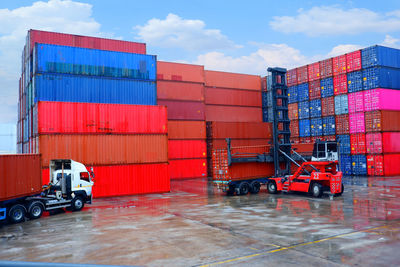 Stack of red metallic structure by building against sky