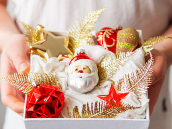 Man holds box with new year decorations. bright red and golden decorative toys for christmas tree.