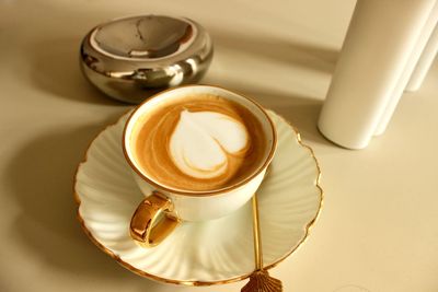 A cup of coffee with a heart symbol on a golden saucer