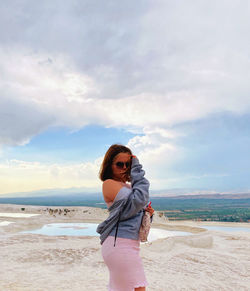 Young woman wearing sunglasses standing on beach