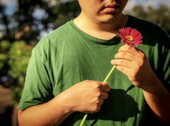 Close-up of man holding flower against blurred background