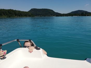 Girl climbing on boat in sea against blue sky