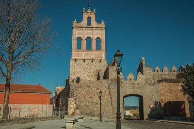 Street going through the carmen gateway on the stone city wall and brick tower in avila, spain.